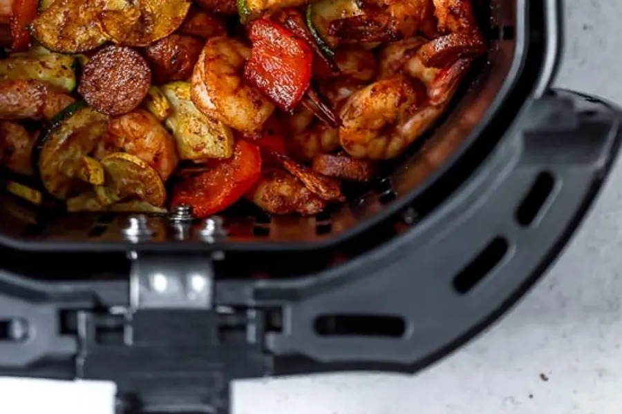 Crevettes cajun avec courgettes et poivrons rouges dans le panier de l'airfryer
